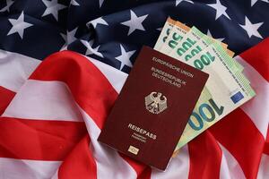 Red German passport of European Union and money on United States national flag background photo