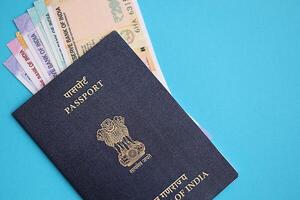 Blue Indian passport and Indian rupees money bills on blue background close up photo