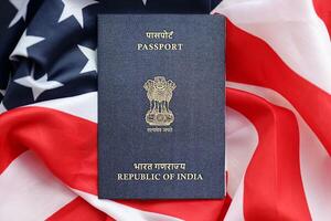 Blue Indian passport on United States national flag background close up photo