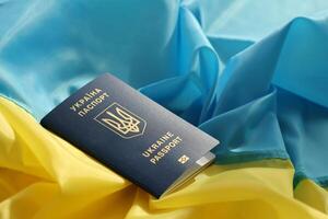 One Ukrainian biometrical passport on folded waving flag of Ukraine country photo