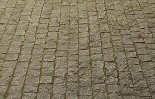 The texture of the paving slab paving stones of many small stones of a square shape under bright sunlight photo