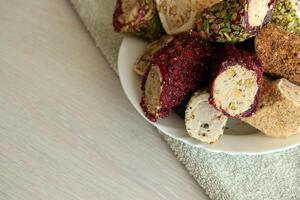 Many rolls of turkish delight with different flavors and fillings in white plate on table. Cuts of Turk Lokumu photo