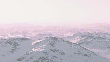 A snow-covered mountain range at sunset with a pink sky video