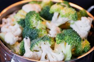 brócoli y coliflor son al vapor en un cacerola - sano dieta, bebé alimento, Cocinando en un buque de vapor foto