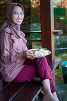 side view of a veiled woman eating fried rice with her gaze facing the camera. photo