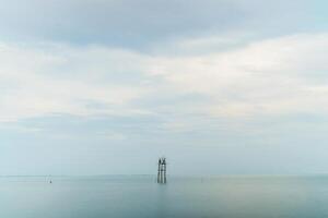 building in the middle of a calm sea with a cloudy sky towards evening. photo
