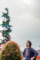 Javanese man is standing with a backpack on his shoulders against a cloudy sky with free space for photocopying. photo