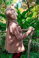 side view of a woman wearing a headscarf holding a safety iron for her hands with an expression facing the camera. photo