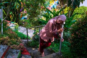 parte superior ver de un mujer vistiendo un Pañuelo propensión en el la seguridad barandilla de el escalera en el jardín. foto