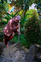 Top view of a woman wearing a headscarf leaning on the safety railing of the stairs in the garden. photo