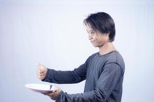 close up view of handsome asian man holding plate with happy expression, showing that the food is delicious on isolated white background for advertising. photo