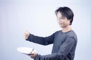 close up view of handsome asian man holding plate with happy expression, showing that the food is delicious on isolated white background for advertising. photo