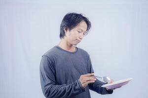 handsome asian man holding empty plate while thinking for serving food menu on isolated white background for advertising menu. menu presentation concept. photo