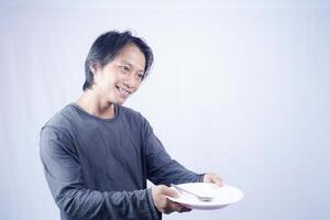 close up view of handsome asian man holding plate with happy expression, showing that the food is delicious on isolated white background for advertising. photo