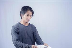 Portrait of Asian men who are hungry holding empty plates to ask to eat with a white background that is isolated for the photocopy space on it. Menu Poet Concept. photo