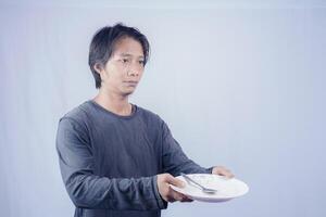 retrato de asiático hombres quien son hambriento participación vacío platos a pedir a comer con un blanco antecedentes ese es aislado para el fotocopia espacio en él. menú poeta concepto. foto