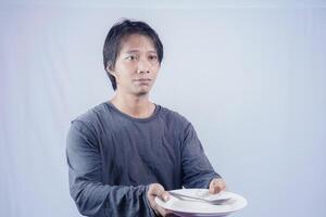 retrato de asiático hombres quien son hambriento participación vacío platos a pedir a comer con un blanco antecedentes ese es aislado para el fotocopia espacio en él. menú poeta concepto. foto