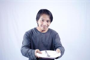 close up view of handsome asian man holding plate with happy expression, showing that the food is delicious on isolated white background for advertising. photo