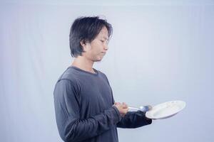 handsome asian man holding empty plate while thinking for serving food menu on isolated white background for advertising menu. menu presentation concept. photo