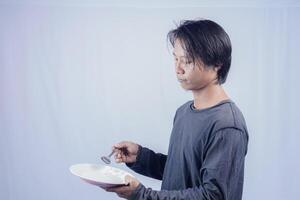 handsome asian man holding empty plate while thinking for serving food menu on isolated white background for advertising menu. menu presentation concept. photo