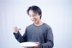 asian man pointing towards empty plate with happy expression isolated white background for coffee photo space. food menu presentation concept.