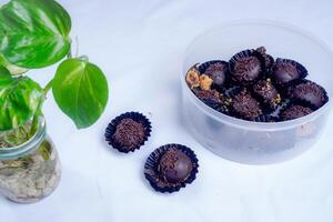 Trisolated chocolate ball cake, close-up view of chocolate ball cake sprinkled with lemongrass on a white background with decorative plants on the side. photo