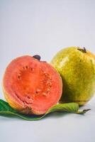 Guava isolated. Collection of red fleshed guava fruit with yellowish green skin on a leaf isolated on a white background. photo