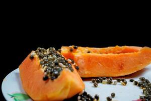 close up view of papaya fruit isolated on plate on black background. photo