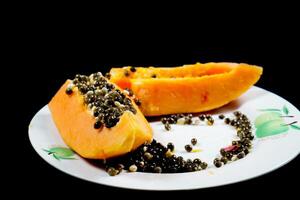 close up view of papaya fruit isolated on plate on black background. photo