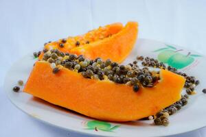 close up view of papaya fruit isolated on plate on black background. photo