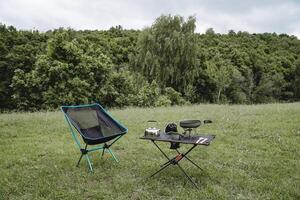 The concept of a tourist holiday in the wild, camping in a clearing in the forest, hiking, a summer vacation in a hike, compact equipment, a folding chair. photo