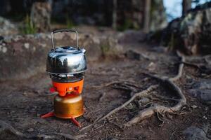 making tea on a gas burner, boiling water on a hike. Orange system for cooking. Camping in nature. photo