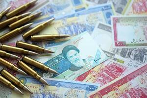 Many bullets and iranian rials money bills close up. Concept of terrorism funding or financial operations to support war photo