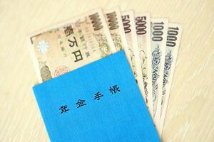 japonés pensión seguro libro en mesa con yen dinero facturas. azul libro para Japón pensionistas foto