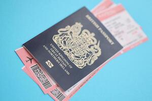 Blue British passport with airline tickets on blue background close up photo