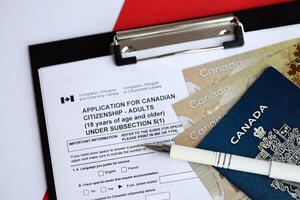 solicitud para canadiense ciudadanía para adultos en mesa con bolígrafo, pasaporte y dólar cuentas foto