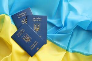 Three Ukrainian biometrical passports on folded waving flag of Ukraine country photo