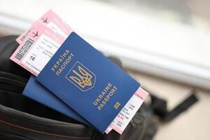 Two ukrainian biometrical passports with air flight tickets on black touristic backpack photo