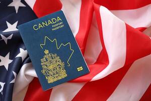 Canadian passport on United States national flag background close up. Tourism and diplomacy photo