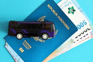 Blue Republic Indonesia passport with money and toy bus on blue background close up photo