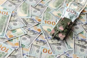 Tank on crumpled hundred dollar bills banknotes. Background of war funding and military support photo