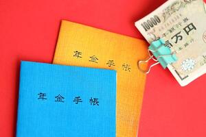 Japanese pension insurance booklets on table with yen money bills. Blue and orange books photo