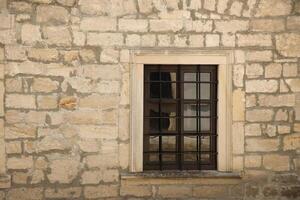 Very old window in brick stone wall of castle or fortress of 18th century. Full frame wall with window photo