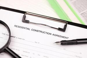 Construction contract form on A4 tablet lies on office table with pen and magnifying glass photo