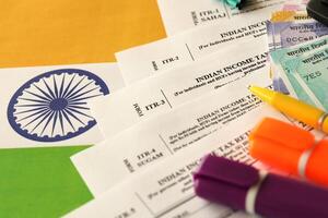 Indian income tax return blank form with pen and indian rupees bills photo