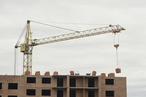 View of a large construction site with buildings under construction and multi-storey residential homes. Tower cranes in action on blue sky background. Housing renovation concept photo