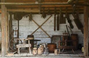 Collection of planers and retro wood saws hang on a wooden wall near an old house. Carpenters plane and other things on wall photo