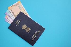 Blue Indian passport and Indian rupees money bills on blue background close up photo