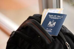 Blue Palestinian Authority passport with airline tickets on touristic backpack close up photo