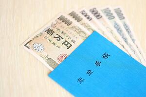 Japanese pension insurance book on table with yen money bills. Blue book for japan pensioners photo